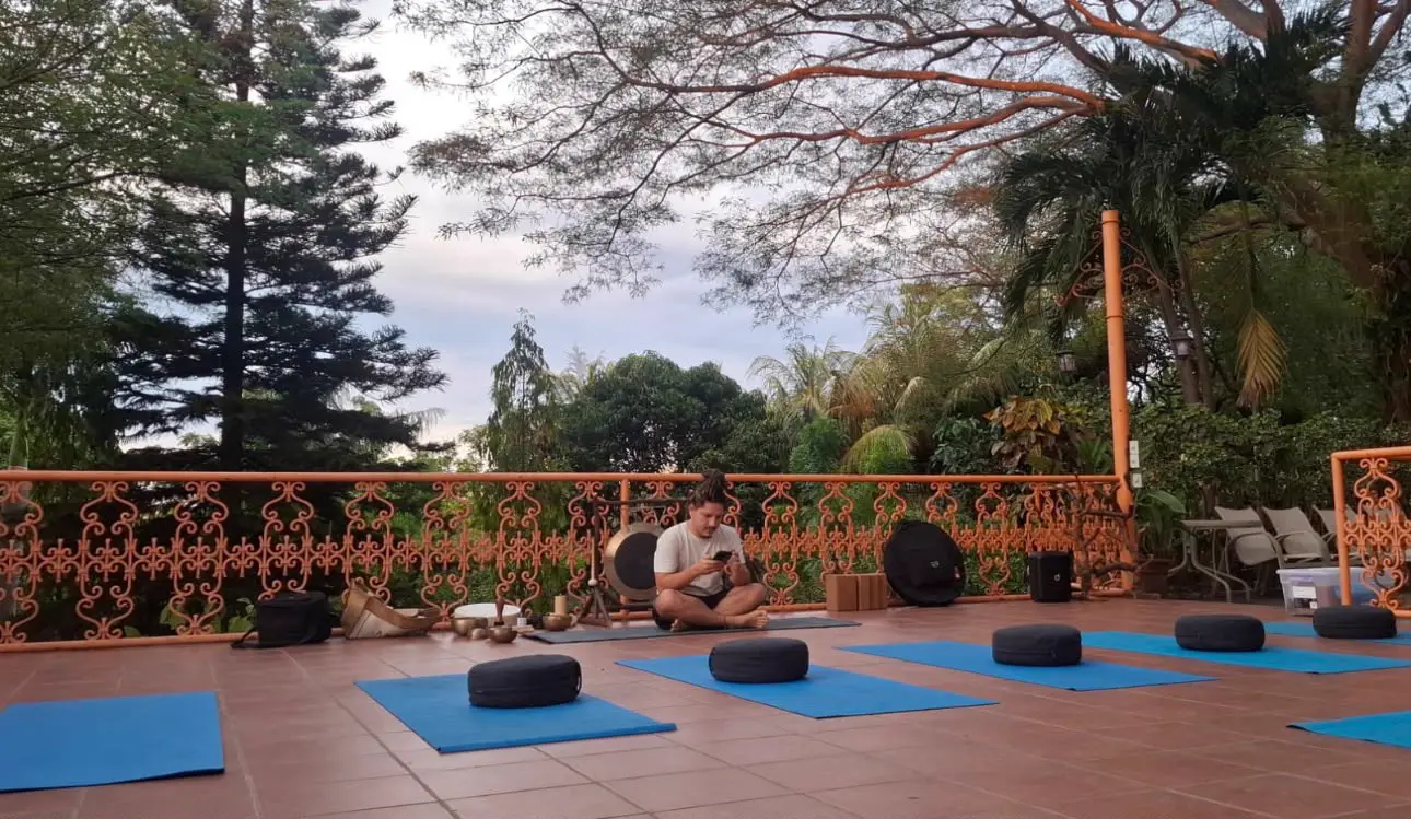 Yoga mats, meditation cushions and sound instruments set up on an open-air terrace among trees